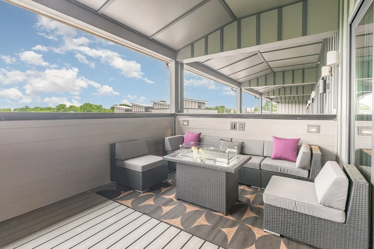 A cozy outdoor seating area featuring a glass table and decorative cushions, surrounded by a tranquil ambiance. The setting is ideal for morning coffee, sunset chats, or group gatherings, and emphasizes comfort and versatility.