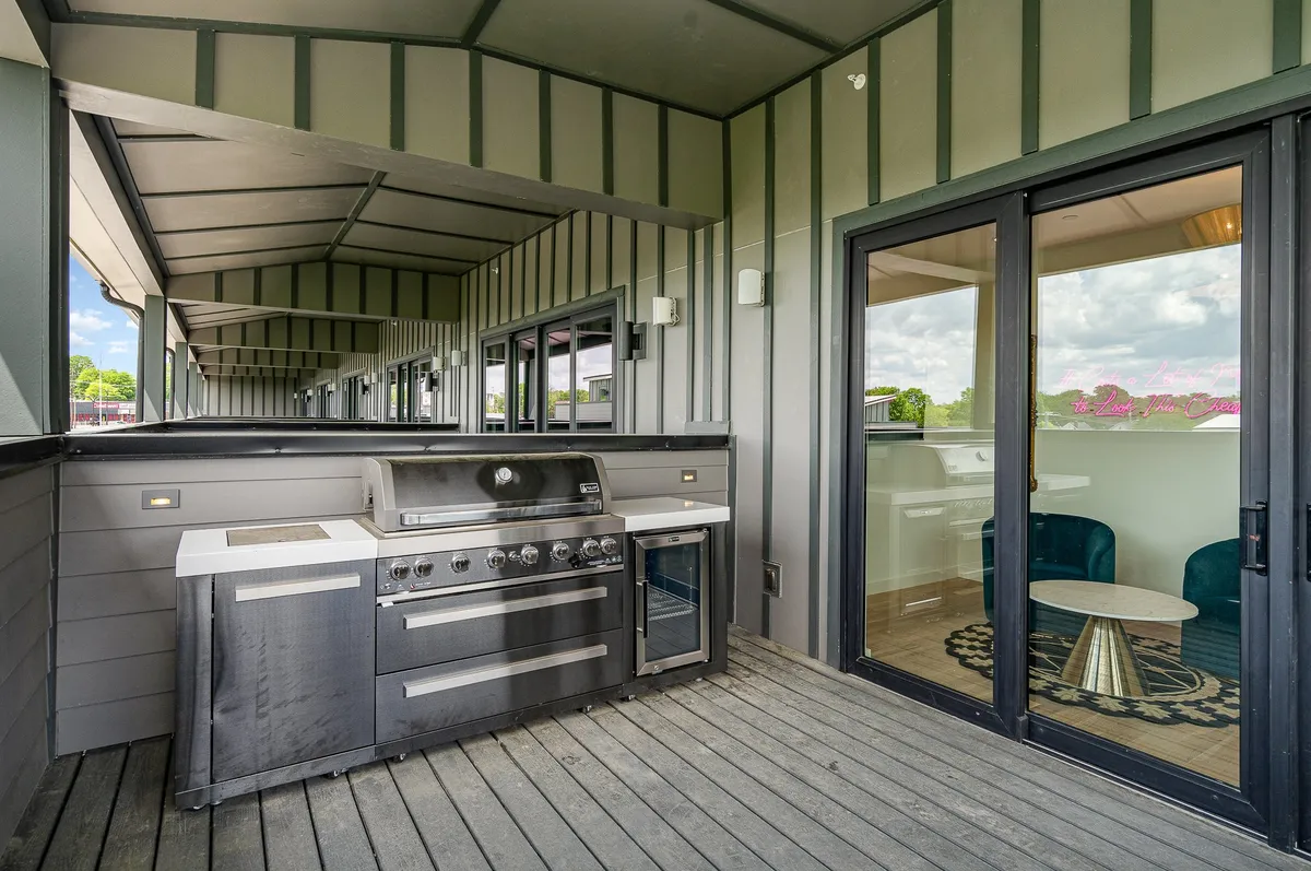 A spacious patio with a modern outdoor kitchen grill and comfortable seating area. Sliding glass doors seamlessly connect this patio with the interior, making it easy to move between indoor and outdoor living spaces.