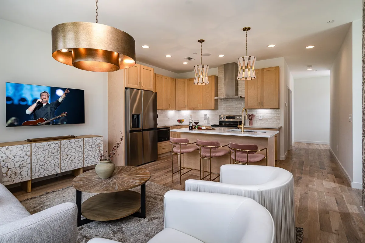 A contemporary kitchen scene with a kitchen island and bar stools, large TV for entertainment, and decorative cabinetry. The space is open, bright, and ready for both cooking and socializing.