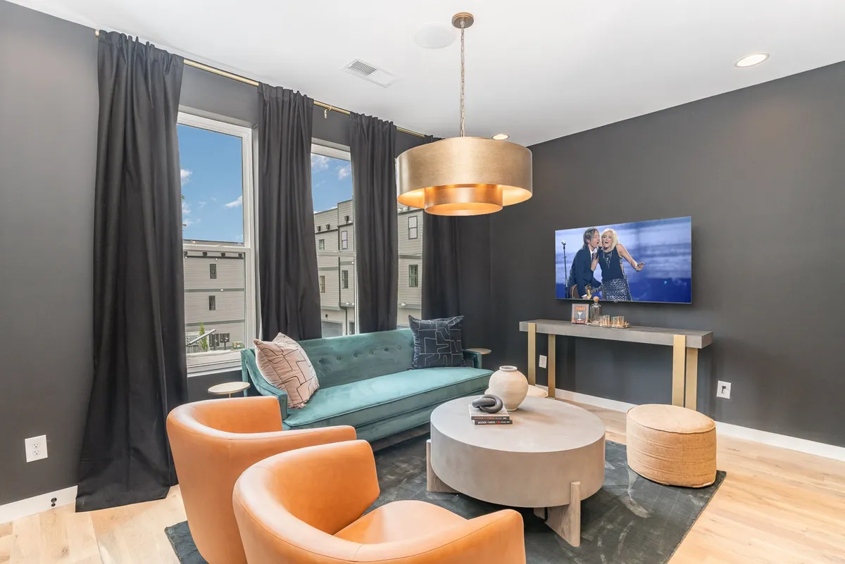 The hero image showcases a spacious, modern living room with a comfortable sofa, stylish coffee table, large smart TV, and a striking light fixture—perfect for relaxing, entertaining, and gathering with friends or family.